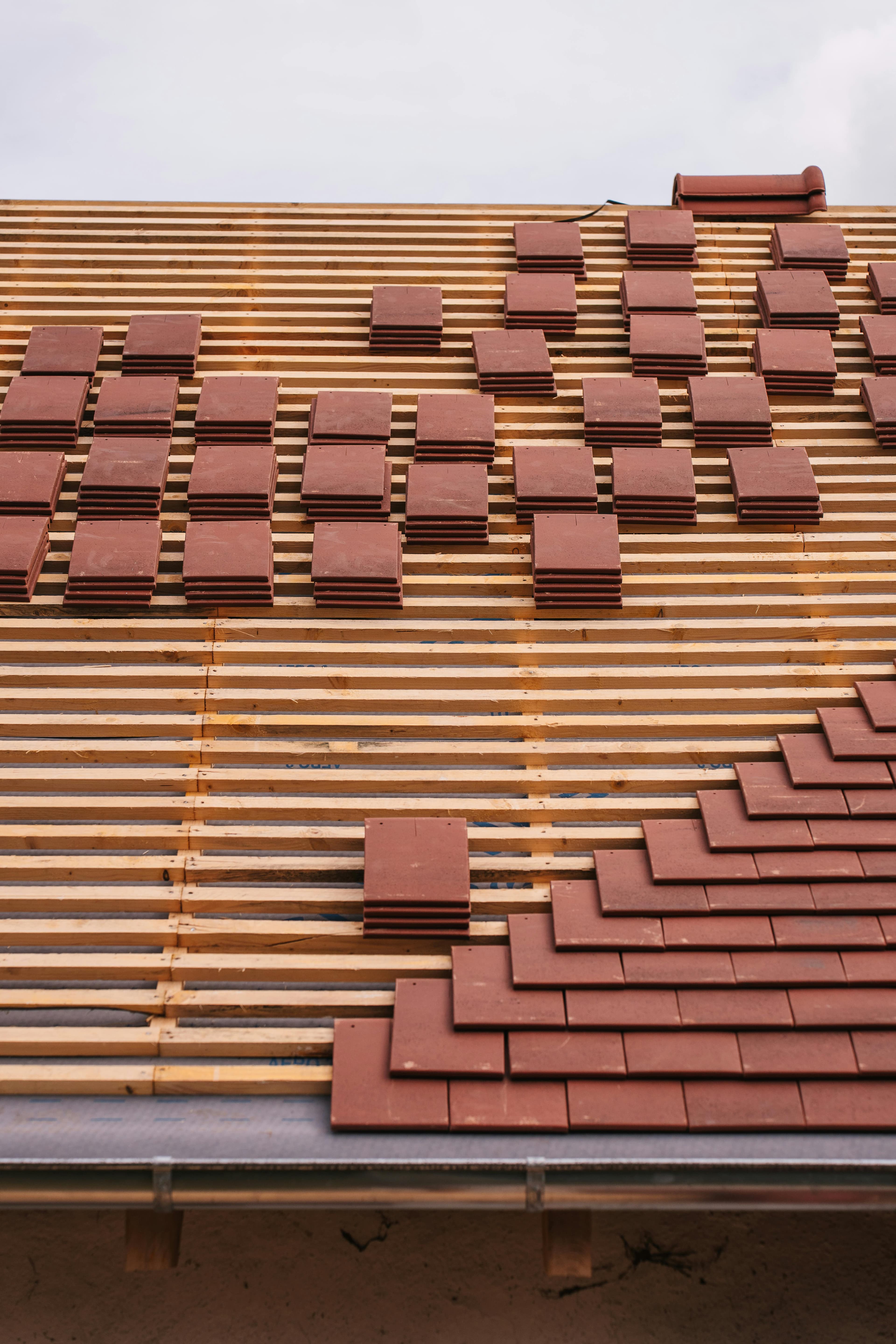 Clay roof tiles being laid on fresh timber battens — roofing craft detail